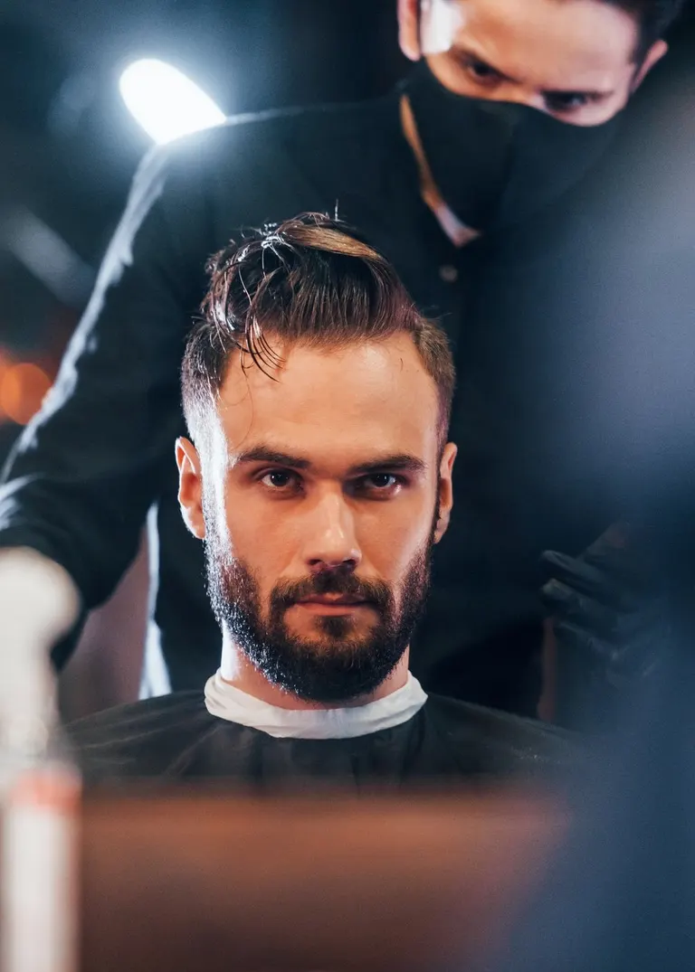 Mann mit Bart beim Haarschnitt im Salon